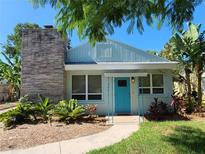 Charming light blue house with teal door, landscaped yard, and stone chimney at 280 46Th Ave, St Pete Beach, FL 33706