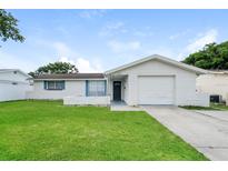 Ranch-style home with white brick exterior, blue accents and a well-maintained lawn at 6912 Amarillo St, Port Richey, FL 34668