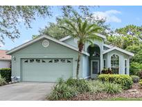 Single-story home with light green exterior, two car garage, and palm tree at 7319 Eleanor Cir, Sarasota, FL 34243