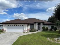 House exterior with a brown roof, white garage door, and green lawn at 234 Antofagasta St, Punta Gorda, FL 33983