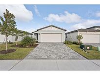 New construction home with gray exterior, paver driveway, and landscaping at 113 Whiteland Bnd, Nokomis, FL 34275