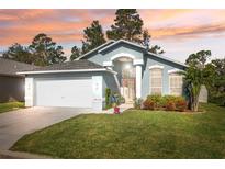 House exterior at sunset, light blue with white garage door at 7940 Fashion Loop, New Port Richey, FL 34654