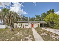 A charming ranch-style home with a red door and landscaped yard at 6445 Skyline Ct, Spring Hill, FL 34606