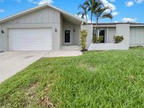 House exterior featuring a single-story home with a two-car garage and manicured lawn at 18978 Mcgrath Cir, Port Charlotte, FL 33948