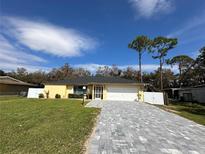 Bright yellow house with gray paver driveway and white fence, offering curb appeal at 20102 Lorenzo Ave, Port Charlotte, FL 33952