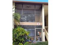 View of the home's exterior featuring a screened balcony with outdoor seating, with green foliage visible at 642 Bird Bay E Dr # 205, Venice, FL 34285