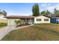 Charming ranch home with a light green exterior, landscaping, and a spacious driveway at 1073 Kenwood Dr, Dunedin, FL 34698