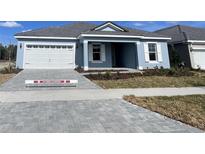 Charming single-story home featuring a two-car garage, neatly landscaped front yard, and light blue paint at 2515 Wise River Lane, Zephyrhills, FL 33539