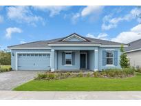 Charming one-story home featuring a blue exterior, well-manicured lawn, and a two-car garage at 2515 Wise River Lane, Zephyrhills, FL 33539