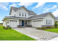 Charming two-story home featuring a three-car garage, stone accents, and well-manicured landscaping at 2626 Wise River Lane, Zephyrhills, FL 33539