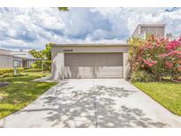 View of the two-car garage with flowering shrubbery on a sunny day at 13619 Twin Lakes Ln # 15, Tampa, FL 33618
