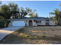 Charming one-story home with a front lawn, a white garage door and an arched front door at 21300 Washburn Ave, Port Charlotte, FL 33952