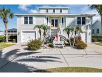 Two-story light green house with a large driveway, landscaping, and palm trees at 4049 Cobia Dr, Hernando Beach, FL 34607