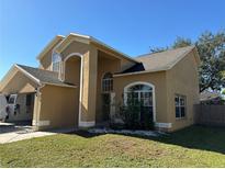 Two-story house with a beige exterior, arched entryway, and landscaped lawn at 1211 Sweet Gum Dr, Brandon, FL 33511