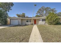 Updated ranch home with a red door and well-maintained lawn at 5023 Thames Dr, New Port Richey, FL 34652