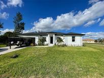 White house with black roof, landscaping, and driveway at 10625 Ayear Rd, Port Charlotte, FL 33981