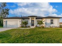 White single-story house with a gray roof, two-car garage, and landscaping at 10625 Ayear Rd, Port Charlotte, FL 33981