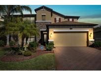 Two-story house with tan siding, stone accents, and a three-car garage at 1726 Cameron Court, Trinity, FL 34655