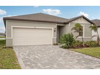 Paver driveway and front yard landscaping of a single-story home at 117 Runaway Field Ave, Nokomis, FL 34275