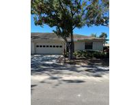 Light beige house with a two-car garage and mature landscaping at 2513 Lancaster Dr, Sun City Center, FL 33573