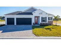 Inviting single-story home with a two-car garage, stone accents, and a red front door at 25494 Calusa Dr, Punta Gorda, FL 33955