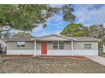 Updated one-story home with gray siding, red door, and landscaping at 11615 Meadow Dr, Port Richey, FL 34668