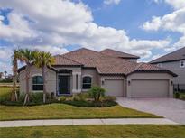 Two-story house with a three-car garage, and palm trees in the front yard at 33161 Kateland Dr, Wesley Chapel, FL 33545