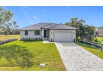 Charming single-story home with well-manicured lawn, grey metal roof and paver driveway at 16760 Acapulco Rd, Punta Gorda, FL 33955