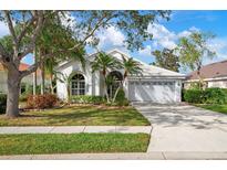 Single-story home with a white exterior, landscaping, and a two-car garage at 5923 Sandstone Ave, Sarasota, FL 34243