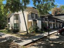 Two story condo building featuring a carport, stairs, and manicured landscaping with large mature trees at 11511 113Th St # 13F, Seminole, FL 33778