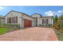 Beautiful single-story home with a red brick driveway, wood shutters, and a two-car garage at 14517 Coastal Woodland Ln, Parrish, FL 34219