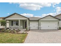 Beautiful one-story home with a three car garage, professional landscaping, and a brick driveway at 1832 Draughton Dr, Zephyrhills, FL 33541