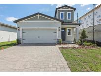 Charming two-story home features a gray exterior, a brick driveway, and a well-manicured lawn at 1852 Brekey Way, Zephyrhills, FL 33541