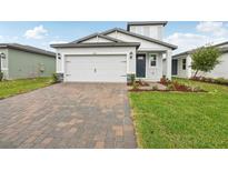Charming single-Gathering home with a brick driveway, two-car garage, and professionally landscaped front yard at 1868 Brekey Way, Zephyrhills, FL 33541