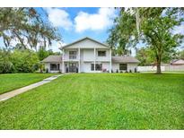 Charming two-story white home with a large lawn and mature trees offering great curb appeal at 11419 Donneymoor Dr, Riverview, FL 33569