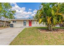 Charming single-story home featuring a well-manicured lawn and vibrant red front door at 7216 E Emma St, Tampa, FL 33610