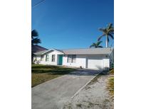 Charming single-story home featuring a two-car garage, well-maintained lawn, and a vibrant turquoise front door at 18686 Van Nuys Cir, Port Charlotte, FL 33948