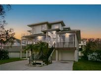 Stunning multilevel modern home with balconies, lush landscaping, and ample parking at 606 Indiana Ave, Crystal Beach, FL 34681