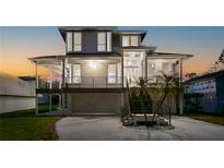 Stunning two-story home with a spacious porch and modern design, showcasing beautiful curb appeal at 606 Indiana Ave, Crystal Beach, FL 34681
