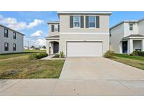 Two-story home featuring neutral siding, a two-car garage, and a well-maintained lawn at 10523 Penny Gale Loop, San Antonio, FL 33576