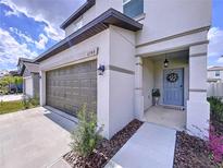 Charming home featuring a two-car garage, gray exterior, and covered front porch at 6744 Back Forty Loop, Zephyrhills, FL 33541