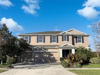 Charming two-story home featuring a well-maintained lawn, three-car garage, and beautiful blue-sky background at 6113 Shadowlake Dr, Apollo Beach, FL 33572