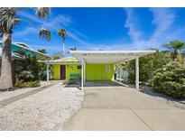 Charming home featuring a covered carport, vibrant colors, and tropical landscaping at 318 182Nd E Ave, Redington Shores, FL 33708
