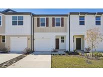 New townhome featuring modern design, attached garage, and manicured landscaping on a sunny day at 11826 Sylvia St, Dade City, FL 33525