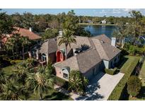 Stunning lakefront home boasts lush landscaping, a circular driveway, and a grand entrance at 7705 Weeping Willow Cir, Sarasota, FL 34241