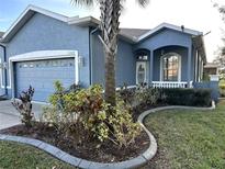 Charming blue home featuring a well-manicured lawn and a welcoming front entrance and attached garage at 12209 Putter Green Ct, New Port Richey, FL 34654