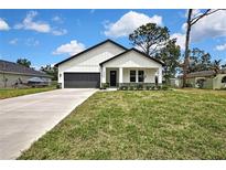 Charming home featuring a modern white exterior, black trim, well-kept lawn, and a two-car garage at 10383 Lear St, Spring Hill, FL 34608