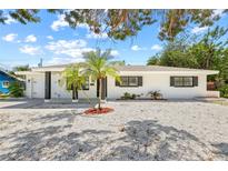 Charming single-story home with white exterior, dark trim, palm trees, and modern landscaping at 1154 64Th S Ave, St Petersburg, FL 33705