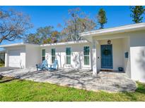 Inviting single-story home with a blue front door, outdoor seating, and a well-manicured lawn at 1767 Colorado Ne Ave, St Petersburg, FL 33703