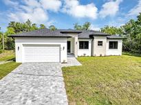 Stunning modern single-Gathering home with a two-car garage, landscaped yard, and a beautiful brick driveway at 82 Venango St, Port Charlotte, FL 33954